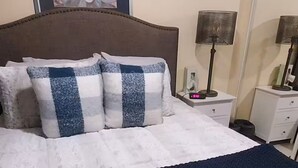 A bed with a dark blue blanket, a headboard, and pillows with a checkered pattern. - Cozy Retreat in Rosarito Near Beaches and Dining (Playas de Rosarito)