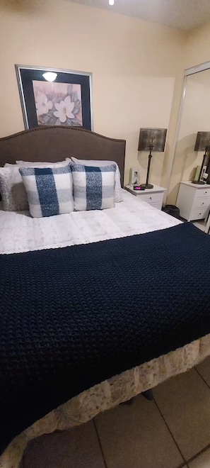 Ein Bett mit einer dunkelblauen Decke, einem Kopfteil und Kissen mit Karomuster.