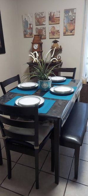A dining table with four chairs, a clock, and decorative wall art. - Cozy Retreat in Rosarito Near Beaches and Dining (Playas de Rosarito)