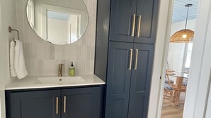 A bathroom with a dark cabinet, a white sink, and a mirror. - FLASH SALE - just steps to beach. 2BR/1BA.Dogs welcome! Perfect ratings. (Englewood)