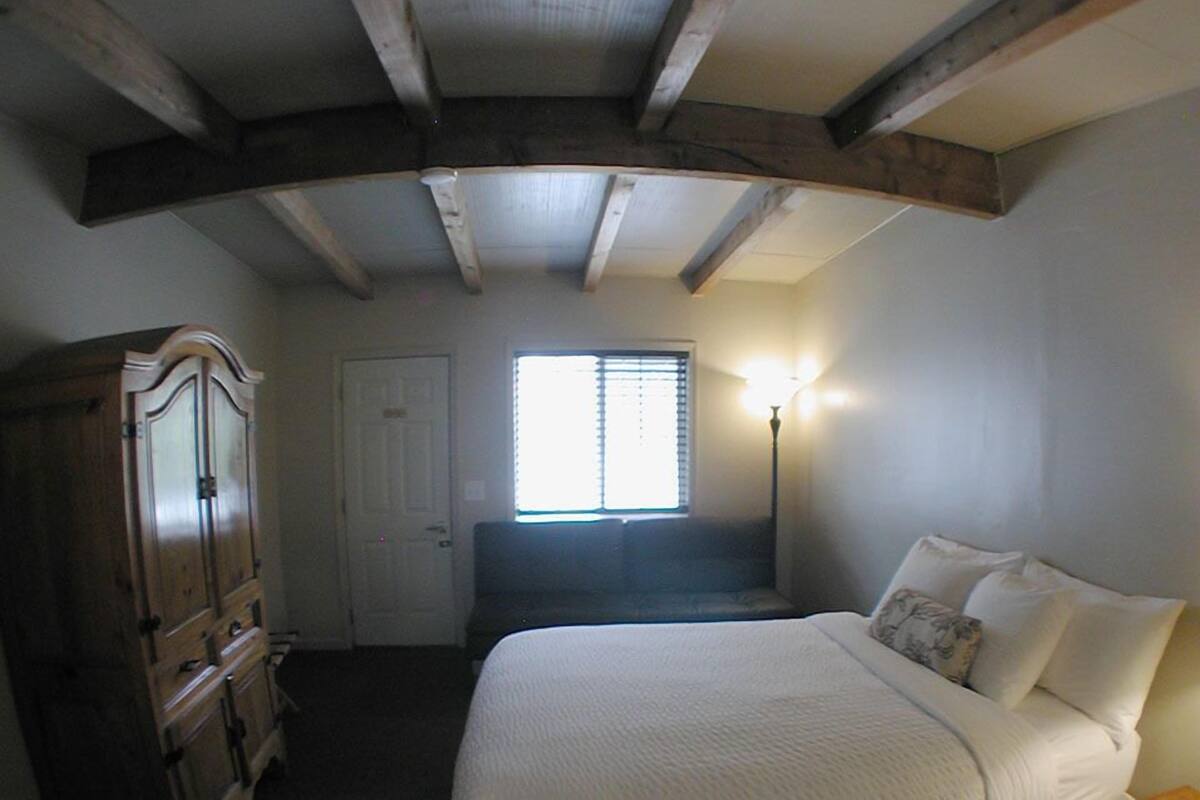 A bedroom with a bed, a wardrobe, a window, and a lamp.