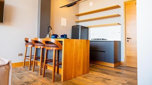 A compact kitchen with a central island, bar stools, and built-in appliances. - MONTECIELO 205 TORRE1 (La Ceja)