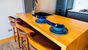 Een keuken met een houten aanrecht, een spoelbak en barstoelen.