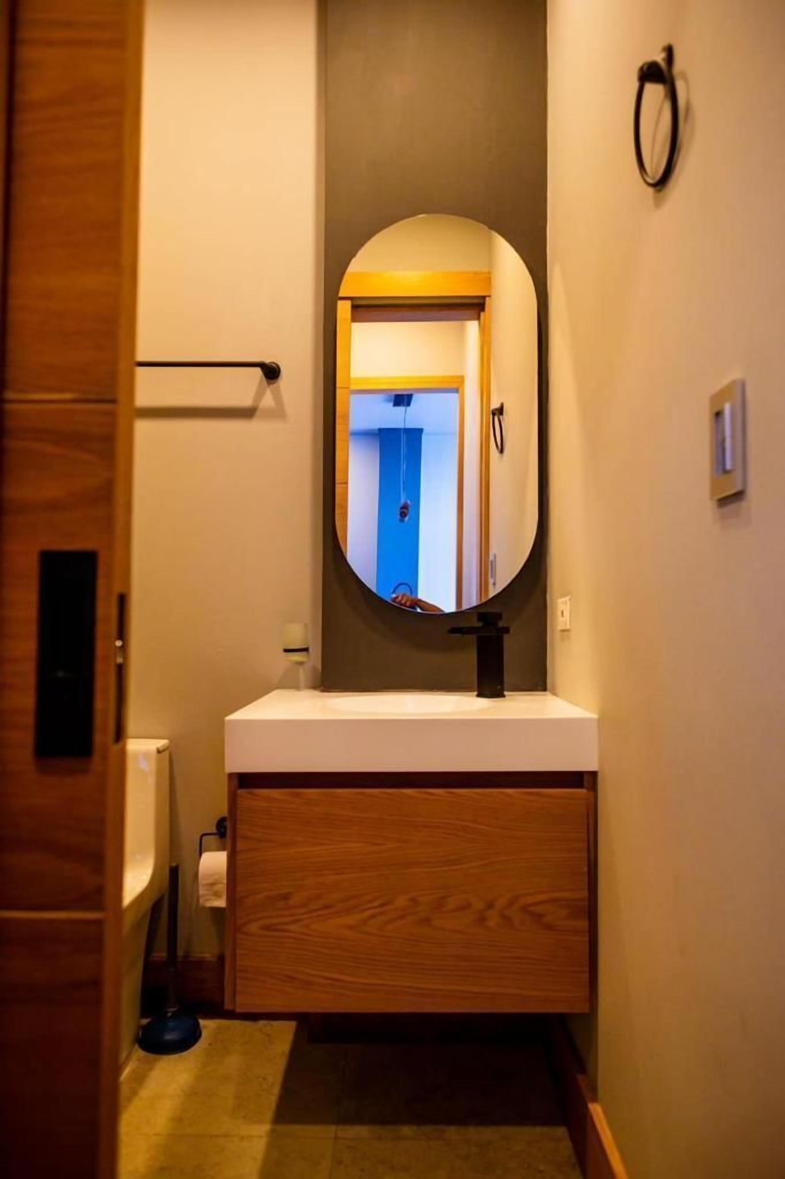 Un bagno con un mobile bagno in legno, uno specchio rotondo e un porta asciugamani.