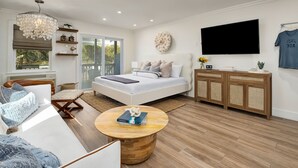 A modern bedroom with a large bed, a TV, a wooden cabinet, and a view of the outdoors. - KC Coastal 30A Inlet Beach • POOL • 1st Floor • KING • 2 Minute Walk to Beach (Inlet Beach)