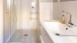 A modern bathroom with a glass-enclosed shower, a large white sink, and a mirror above it.