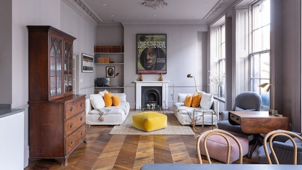 A spacious living room with a fireplace, a wooden cabinet, and a large window providing natural light.