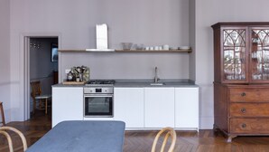 A compact kitchen with white cabinetry, a built-in oven, and a gas stove. There is a wooden cabinet with glass doors on the right.