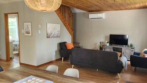 Ein modernes Wohnzimmer mit einem dunkelgrauen Sofa, einem schwarzen Sessel und einer Holztreppe.