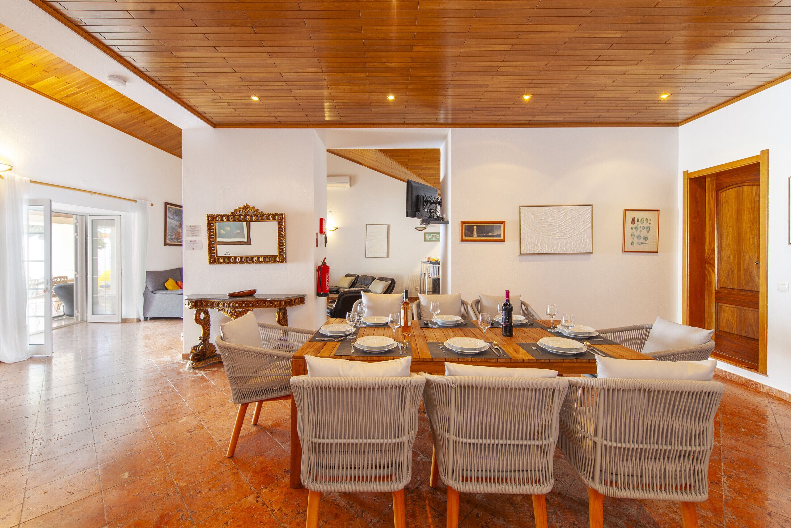 Un coin repas avec une table en bois dressée pour six personnes, entourée de chaises en osier.