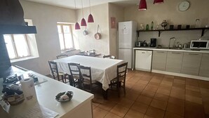 Une cuisine équipée d’une table à manger, de chaises, d’un réfrigérateur et de luminaires suspendus rouges.