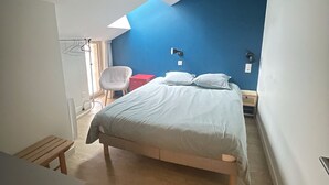 Une chambre à coucher avec un lit, une chaise, un bureau et une lampe.