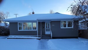 Een huis met twee verdiepingen, een met sneeuw bedekte nok en een zichtbare schoorsteen.