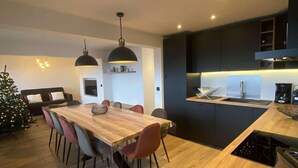 Une cuisine moderne avec une table à manger en bois, des meubles de rangement noirs et un four encastré.