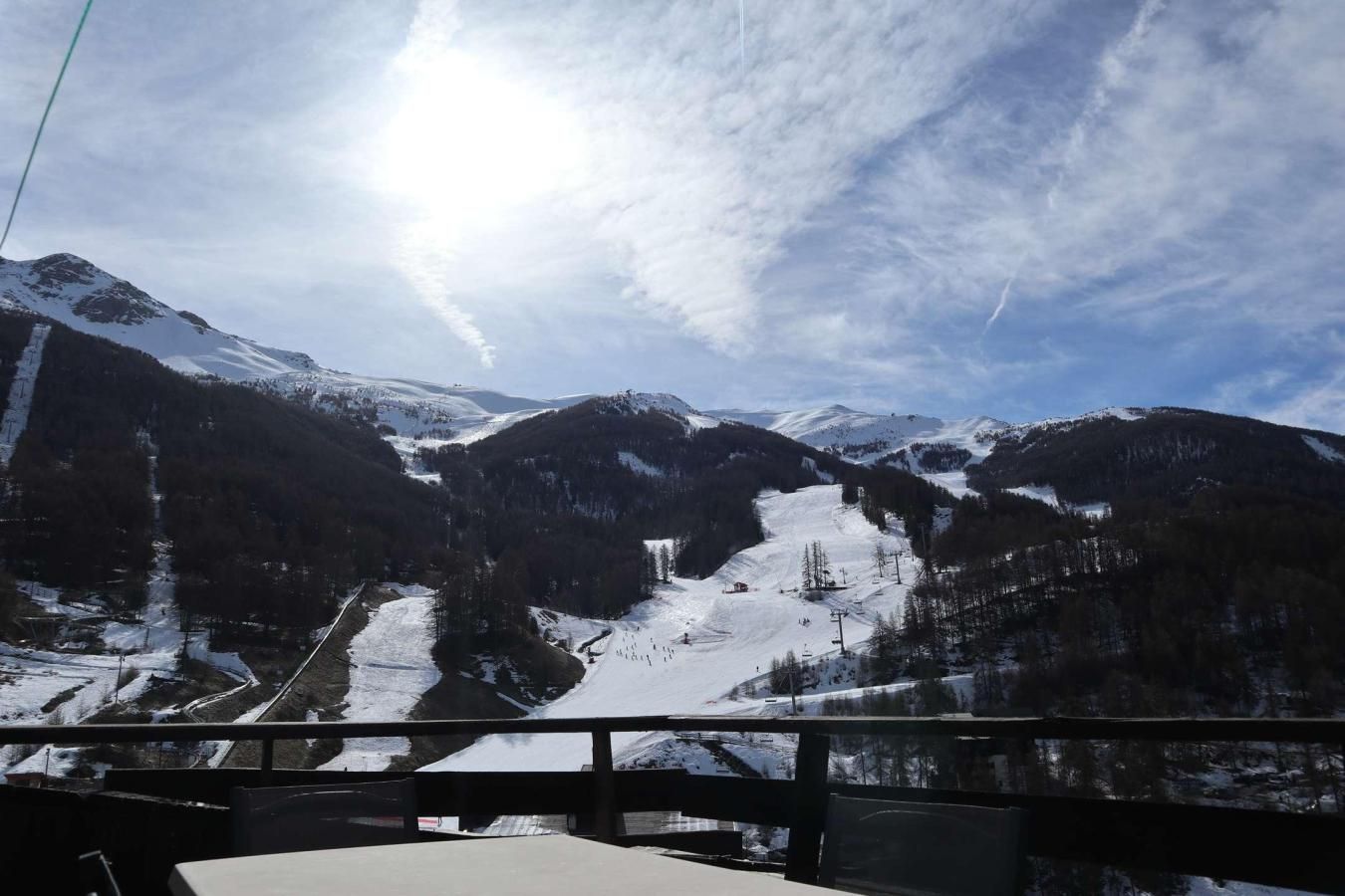 Een bergachtig landschap met een door sneeuw bedekte vallei, een skilift en een heldere lucht.