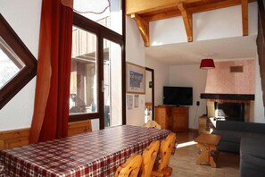 A cozy room with a wooden table, a television, and a fireplace.
