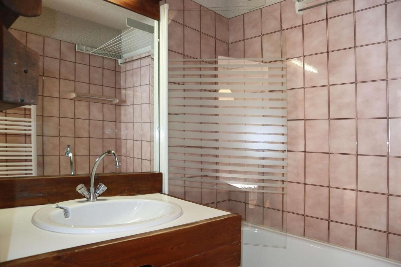 Casa de banho com lavatório, espelho e zona de duche.