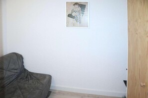 A room with a single framed picture on the wall, a dark-colored sofa, and a wooden door.