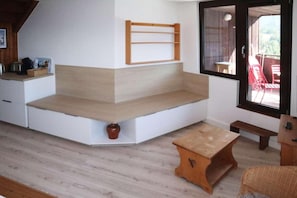 A corner seating area with built-in shelves, a small table, and a window with a view.