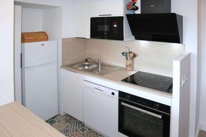 A compact kitchen with a built-in dishwasher, a microwave, a stove, and a sink.