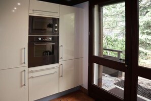 A modern kitchen with stainless steel appliances, white cabinetry, and a large window offering a view of the outdoors. - Chalet, 10m from ski slopes, view valley, terrace, fireplace or stove, tv, 100m², Les Orres (Les Orres)