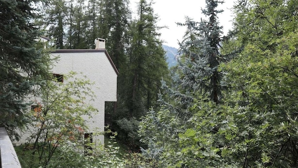 A white building with a sloped roof surrounded by dense forest and mountains in the background. - Chalet, 200m from shops, view valley, terrace, fireplace or stove, tv, 100m², Les Orres (Les Orres)