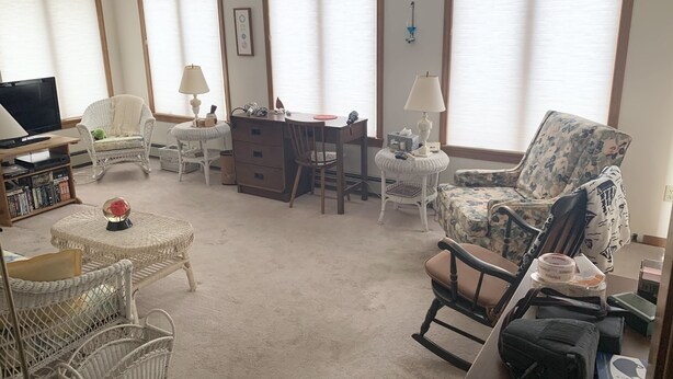 Un salon équipé d’un téléviseur, de meubles en osier, d’un bureau et d’une chaise.