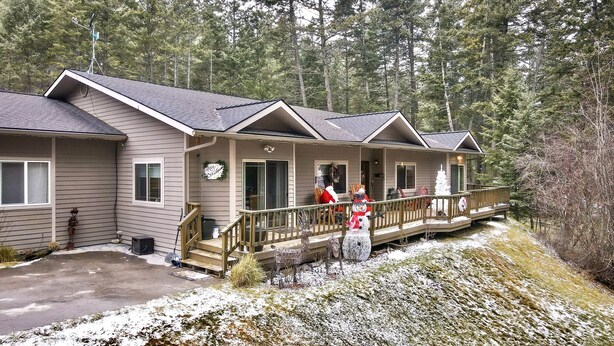 Une cabane avec une véranda, une terrasse et un sol recouvert de neige.