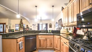 Une cuisine avec des meubles en bois, une cuisinière en acier inoxydable et un plan de travail en granit.