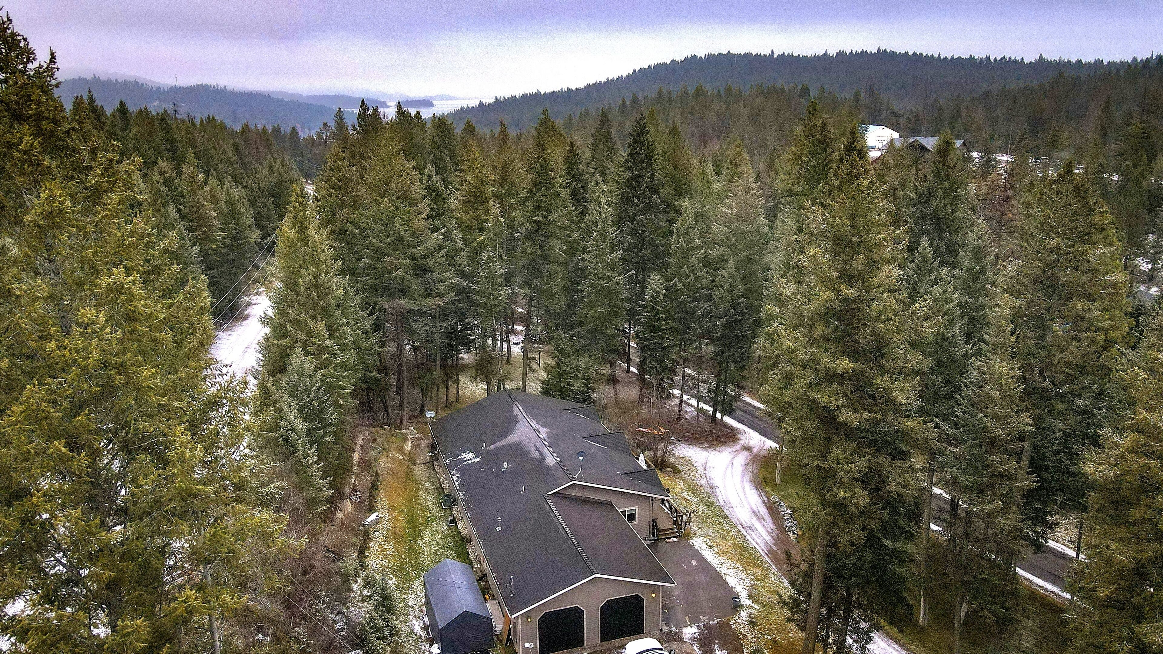 A house surrounded by dense forest with a clear view of the surrounding mountains.
