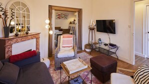 Una sala de estar acogedora con chimenea, un sofá cómodo, una silla, una mesa de centro y un televisor.