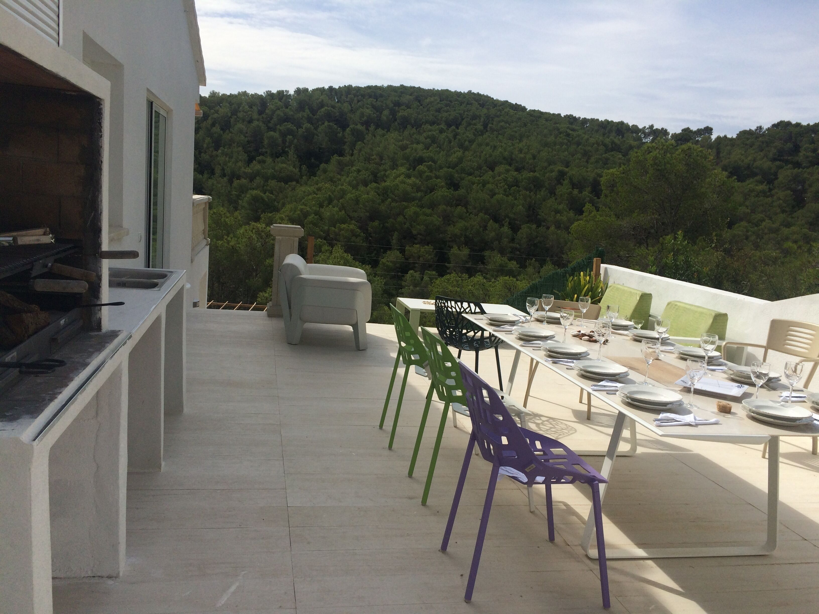 An outdoor dining area with a terrace overlooking a forested hillside.
