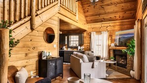 Un intérieur de chalet chaleureux comprenant un espace de vie, une cuisine et une cheminée.