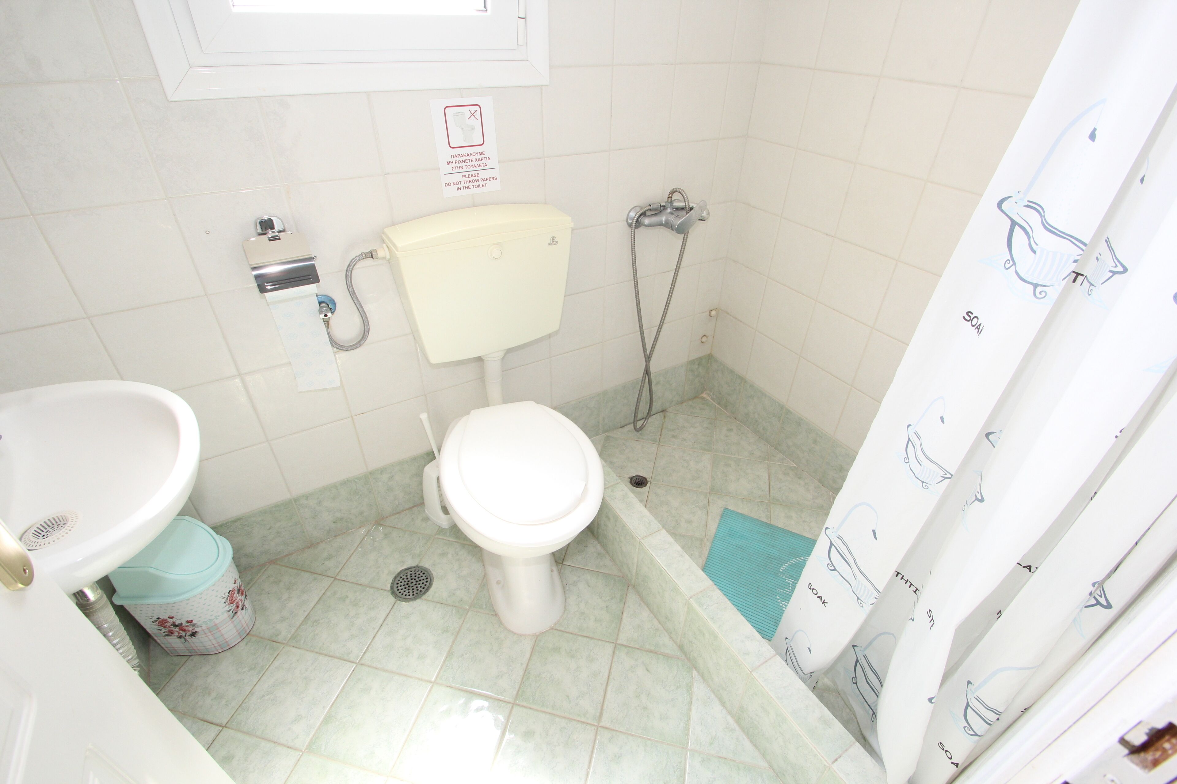 A small bathroom with a toilet, sink, and shower.