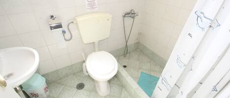 A small bathroom with a toilet, sink, and shower.