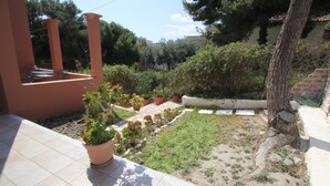 A courtyard with potted plants, a tree, and a tiled patio area.
