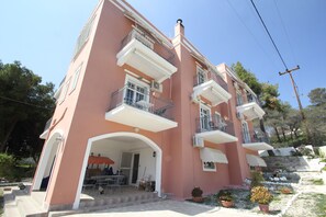 Un edificio rosa con balcones, mobiliario exterior y plantas en macetas.