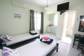 Una habitación con dos camas, televisión y kitchenette.