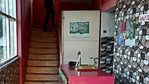 A hotel lobby with a staircase, a reception desk, a fire extinguisher, and a wall with a mosaic pattern. - Wonder Inn Lodge (Ramanagara)