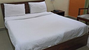 A neatly made bed with white linens in a hotel room. - Wonder Inn Lodge (Ramanagara)