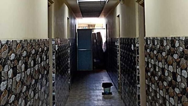 A hallway with patterned stone walls, a tiled floor, and a ceiling with recessed lighting. - Wonder Inn Lodge (Ramanagara)