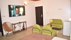 A living room with a television, a sofa, a coffee table, and a chair. -  Bulon Hotel (Yaoundé)