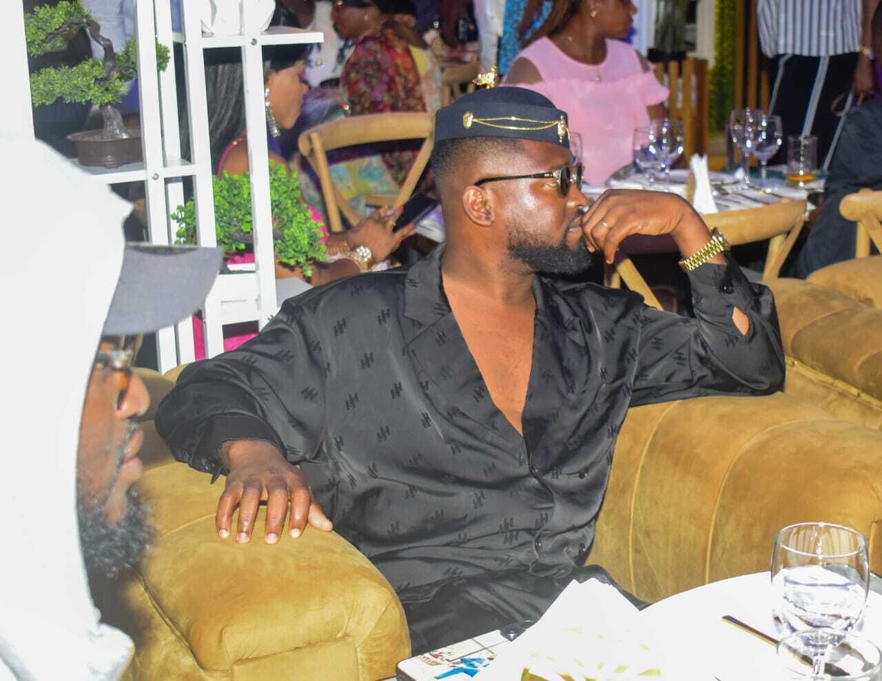 A man seated at a table in a restaurant with a white tablecloth, glasses, and a menu.
