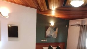 A hotel room with a bed, a desk, two green armchairs, a vase with flowers, and a painting on the wall. -  Bulon Hotel (Yaoundé)