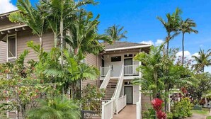 Una casa de dos pisos con balcón, rodeada de vegetación tropical.
