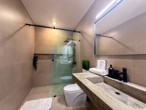Enjoy a refreshing shower in the bathroom, featuring a glass-enclosed shower, large mirror, and vanity with sink.