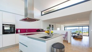 Una cocina moderna con una isla central, horno empotrado y un amplio ventanal con vista a la ciudad.
