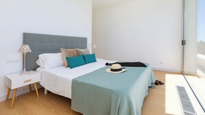Un dormitorio con cama, mesita de noche y ventana.