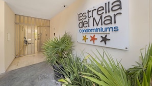 Schild für die Eigentumswohnungen 'Estrella del Mar' mit modernem Eingang und Pflanzgefäßen.