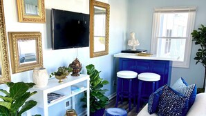 A modern living room with a white sofa, blue ottomans, and a TV on the wall. - Summer Special June 20-27, July 6-11, July 25-Aug 1. Sleeps 12 and pet friendly  (Lavallette)
